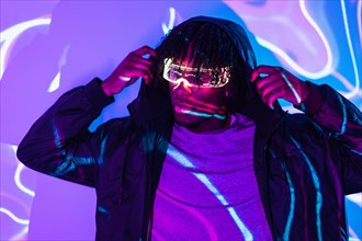 Studio portrait with purple and blue neon lights of a cyber man with futuristic smart goggles