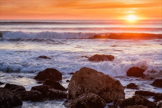 Atlantic ocean sunset with waves and rocks at Costa da Caparica