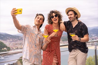 Happy friends taking selfie during a roof party with sea views on holidays