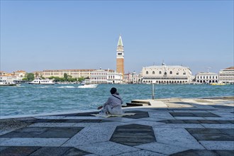 Woman having a picnic in the square in front of the church of San Giorgio Maggiore on the Giudecca Canal with a view of the Doge's Palace