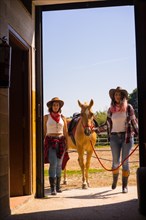 Two cowgirl women enjoying with a horse on a horse riding
