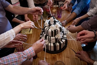 Hands pulling the ribbons of the wedding cake