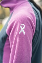 Side view of a woman wearing a sweatshirt with an embroidered cancer awareness ribbon. Vertical Shot