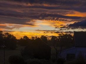 Colourful sunrise with cloud colouring and old farmhouse