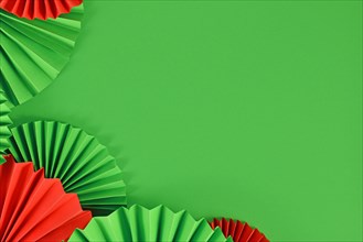 Red and Green paper craft rosettes in traditional Christmas colors on side of green background with empty copy space