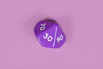 Single pentagonal D10 roleplaying RPG dice on violet background