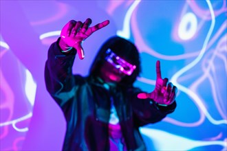 Studio portrait with purple and blue neon lights of an afro futuristic man picturing the future gesturing with hands