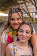A closeup shot of two young Caucasian hugging females with LGBT pride flag outdoors