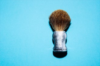 Top view of a shaving brush against a blue background