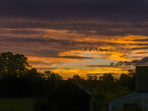 Colourful sunrise with cloud colouring and old farmhouse