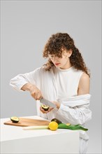 Young woman taking out avocado seed with knife