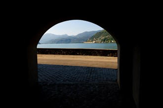 Old Beautiful Street Tunnel with Arch from Brusino Arsizio on the Waterfront in a Sunny Summer Day and with Lake Lugano and Mountain View over Morcote