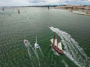 Aerial drone view of tall ships with sails sailing in Tagus river towards the Atlantic ocean in Lisbon