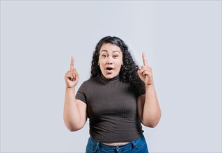 Young latin girl amazed pointing a promotion up isolated. Young curly-haired woman pointing up. Latin people pointing up