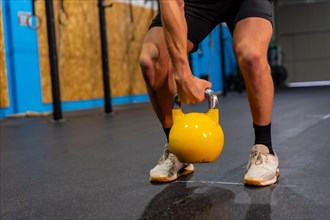 Legs of a disabled man exercising with a kettlebell in a cross training gym