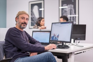 Portarit of a proud man smiling at camera while working in a modern co-working office