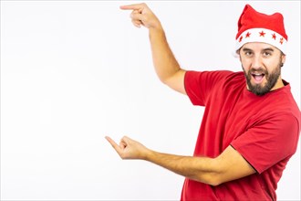 Young very happy Caucasian man with red Christmas hat pointing to the left on a white background