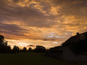 Colourful sunrise with cloud colouring and old farmhouse