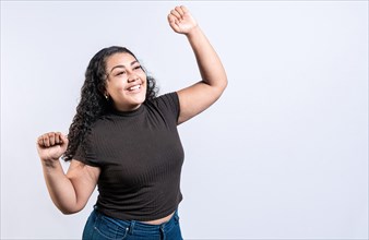 Excited latin girl raising arms celebrating victory. Happy young woman raising arms in victory gesture isolated. Winning people celebrating triumph