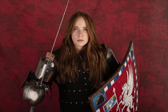 History of the Middle Ages. Portrait of a beautiful medieval female knight in armour on a red background