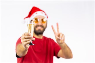 Very happy young Caucasian man with red Christmas hat toasting with a glass of champagne on a white background
