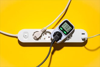 Top view of an energy cost meter in a power strip against a yellow background