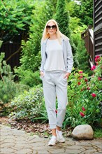 Sporty woman posing in grey tracksuit in the garden