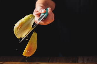 Woman cutting a pear in half with a knife in the air spilling water