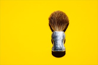 Top view of a shaving brush against a yellow background