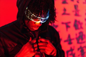 Close-up studio portrait with red neon lights of a futuristic afro man with smart glasses