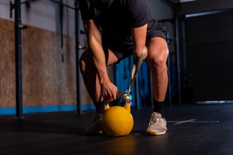 Dark portrait with artificial light on an unrecognizable disabled man exercising with a kettlebell