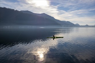 Woman in a Kayak and Using Smartphone on Lake Lugano with Sunlight and Mountain in Ticino