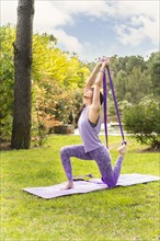 Mid adult female exercising yoga with strap