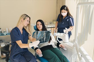 Latina female dentist explaining Tooth X-Rays To A Patient