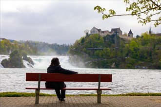 Woman Sitting on a Bench in Front of Rhine Falls at Neuhausen