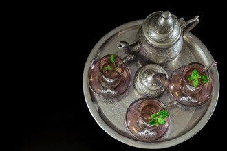 Top view of a traditional Moorish mint tea service on a tray with decorated glassware and silver teapot and sugar bowl