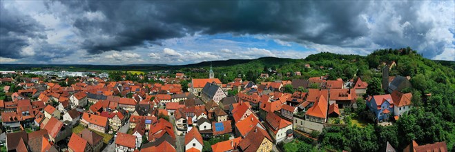 Aerial view of Koenigsberg in Bavaria. The city is surrounded by hills and forests. The sky is cloudy and dark