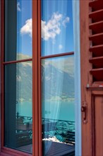 Window View with Reflection from The Historical Grandhotel Giessbach with View over Mountain and Lake Brienz with Sunlight in Giessbach