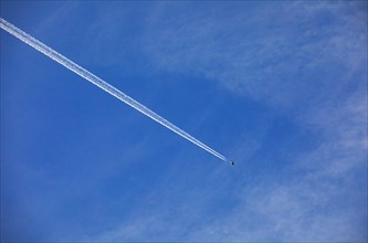 Commercial aircraft with contrails against the blue sky