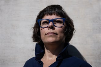 Headshot on a Elegant Woman with Eyeglasses and Leaning on a Concrete Wall in a Sunny Day in Switzerland