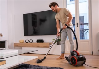 Man using vacuum to clean the living room in the house sharing housework