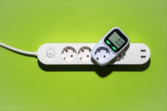 Top view of an energy cost meter in a power strip against a green background