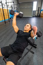 Vertical photo of a strong disabled man exercising with dumbbells in a bench