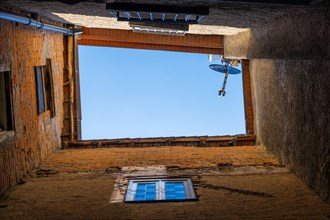 View from Directly Below an Old Building with Patio and Satellite Antenna and Blue Sky in Switzerland