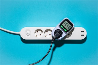 Top view of an energy cost meter in a power strip against a blue background