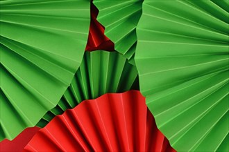 Abstract background with red and green paper craft rosettes in traditional Christmas colors