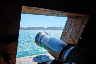 Sea view over the gun cannon muzzle from a gunport in hull of the ship. Gun deck of a sailing ship of Age of Sails