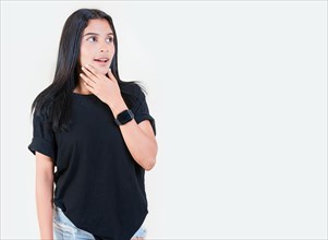 Surprised teen girl looking at an advertisement to side. Surprised Latin girl looking at a promotion to the side. Amazed people with hand on chin looking at blank space