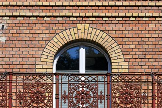 Clinker facade with arched window and richly decorated balcony railing