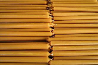 Pile of new yellow wax candles used in churches